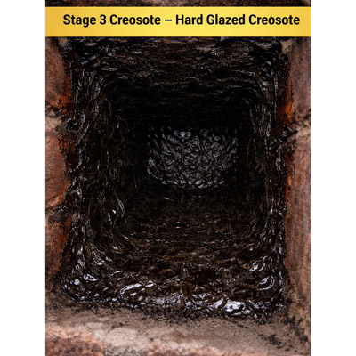 Stage 3 creosote in a chimney: hard glazed creosote with shiny black coating on chimney flue walls.